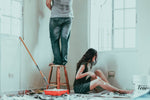 A man and a woman painting the walls of a bedroom in their home.