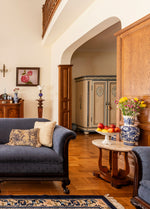 Traditional style interior.  Ornate wood-framed furniture with blue cusshionss.  Hardwood floors and curving wood side table.